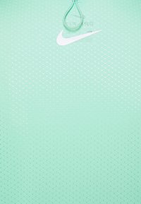 Camiseta deportiva Nike verde menta con el logo en forma de swoosh blanco y un cordón verde claro en el cuello, que presenta un sutil patrón de puntos.