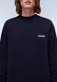 Marineblauwe sweatshirt met een ronde hals, lange mouwen en een klein wit logo op de borst. Glad materiaal met ribgebreide manchetten.