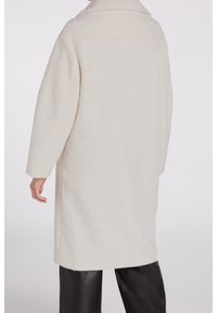 Lyscreme oversized frakke i struktureret stof. Har en notch krave, sidelommer og dropped shoulders. Glat, varm finish.