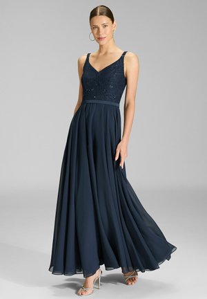 Donkerblauwe avondjurk met een kanten lijfje, V-hals en een vloeiende chiffon rok. Voorzien van spaghettibandjes en een getailleerde taille.