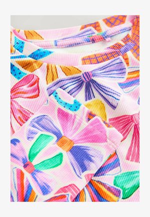 Tejido acanalado con un patrón de lazos coloridos en rosa, violeta, verde, naranja y azul sobre un fondo claro. Los acentos incluyen diferentes estilos de lazos.