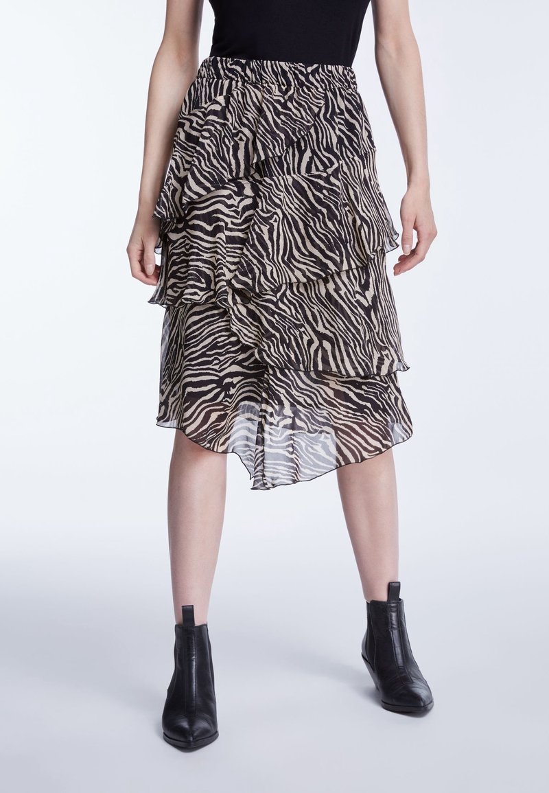 Lagdelte, gennemsigtige nederdel i zebra print med voluminøse lag og elastisk talje. Bæres med ankelhøje sorte støvler.