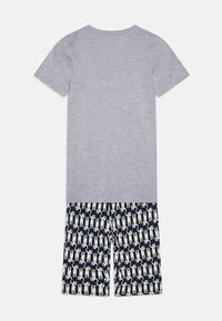 Camiseta de algodón gris de manga corta con pantalones cortos azul marino que presentan un patrón de impresión de animales en crema repetido. Diseño casual y cómodo.