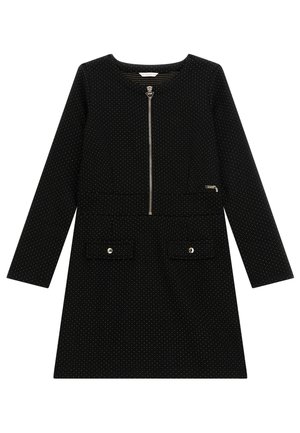 Vestido negro de manga larga con pequeños lunares blancos, cremallera frontal, dos bolsillos con solapa y botones, y detalle del logo de la marca en el pecho.
