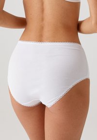 Witte katoenen slips met een naadloos ontwerp, voorzien van een delicaate kanten rand rond de tailleband en beenopeningen. Zachte, gladde textuur.