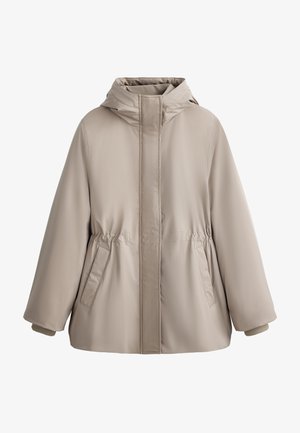Veste matelassée beige avec capuche, présentant une fermeture éclair à l'avant, une taille élastique et deux poches latérales. Texture lisse et coupe légèrement oversize.