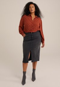 Blusa de manga larga color óxido con detalle de botones y un sutil estampado, combinada con una falda lápiz de mezclilla oscura con una abertura frontal. Botines gris claro.