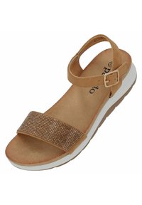 Braune Sandale mit einem breiten, flachen Riemen, der kleine, glänzende Akzente aufweist. Gepolsterte Fußbett, sicherer Knöchelriemen und weiße, strukturierte Sohle.