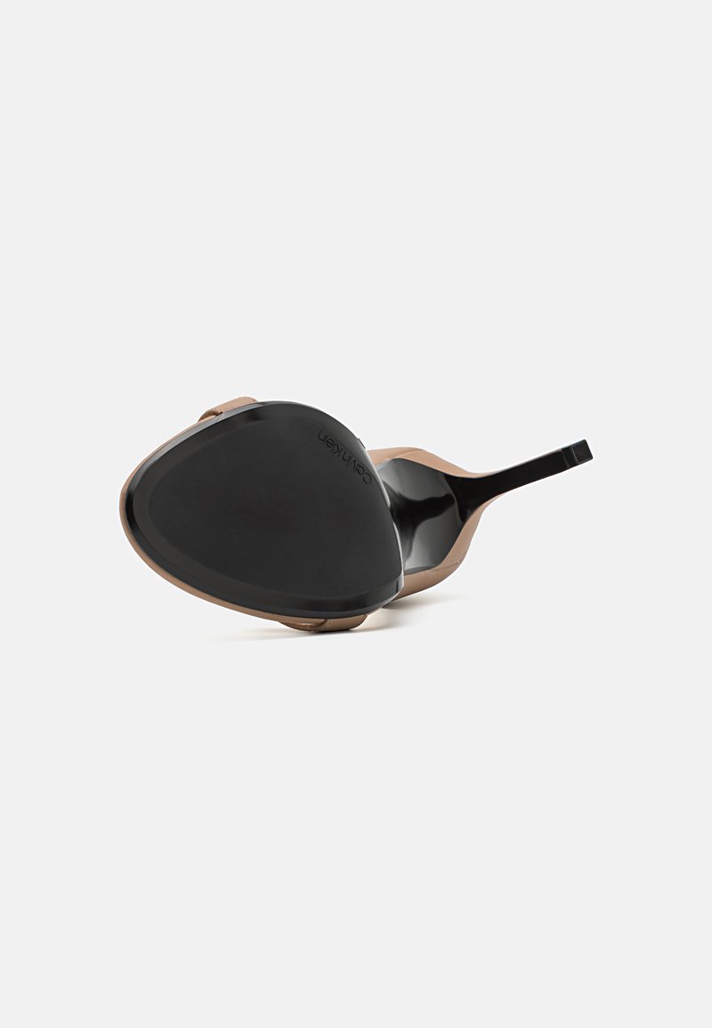 Chaussure à talon avec une semelle noire brillante et un dessus en synthétique beige. Présente une forme de pied triangulaire et un fin talon noir.