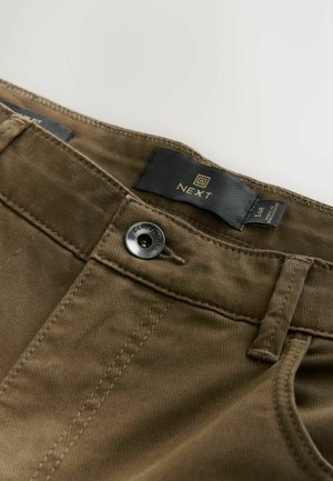 Bruine katoenen broeken met een gestructureerde afwerking, voorzien van een metalen knoop en een merklabel in het zwart. Zijkanten met zichtbare stiksels.