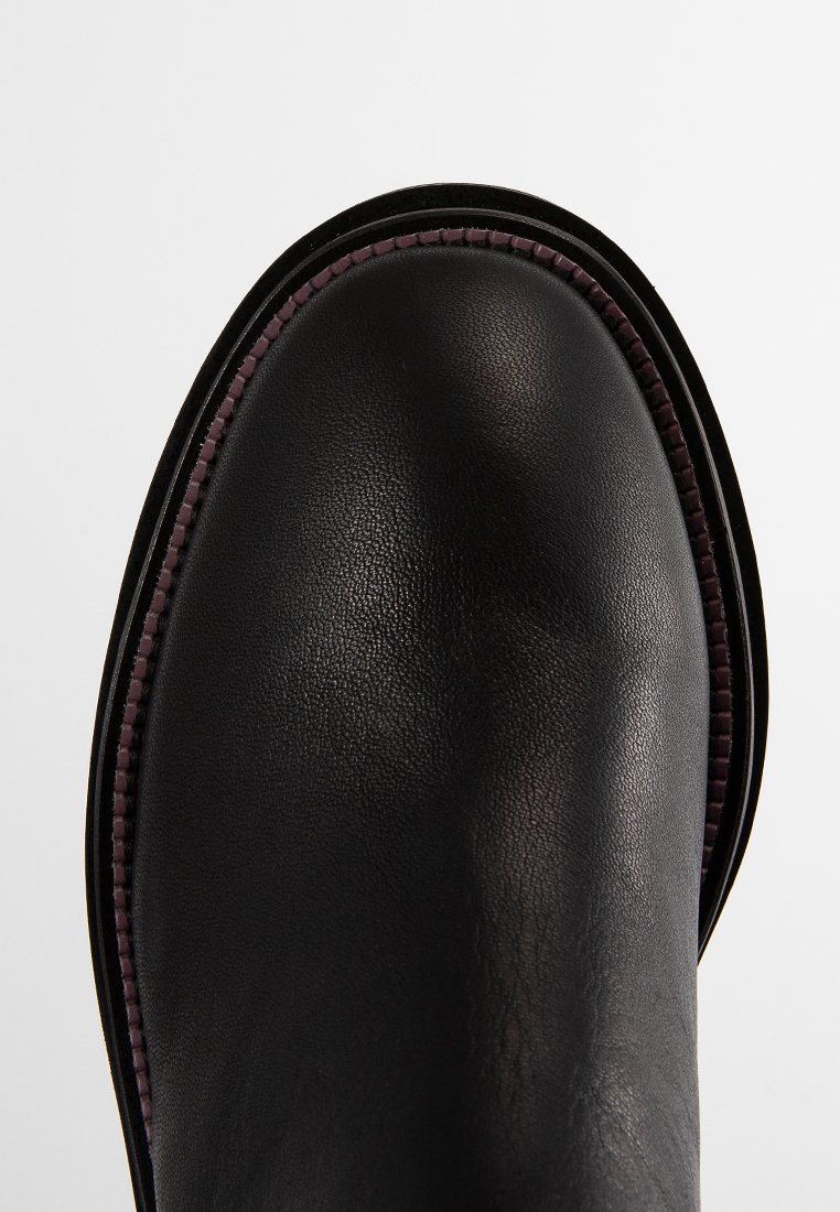 Schwarze Leder-Ankle-Boots mit runder Zehenpartie, strukturierter Oberfläche, kontrastierendem lila Nähten und einem schlanken, minimalistischen Design.