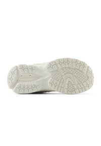 Light-colored athletic shoe sole featuring a rubber texture, detailed tread patterns, and a slight curvature for stability.