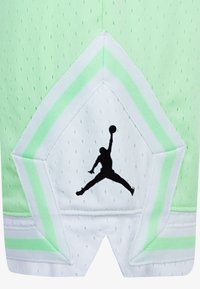 Basketbalové šortky s světle zelenými a bílými panely, zdobené černým logem Jumpman, zobrazujícím basketbalistu skákajícího s míčem.