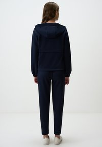Set di felpa con cappuccio e pantaloni coordinati di colore blu navy, realizzato in materiale morbido, caratterizzato da una vestibilità comoda, polsini elasticizzati e cappuccio.