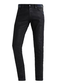 Černé slim fit pánské džíny s předním zapínáním na knoflík a kapsami, mírně pomačkaná textura látky, vystavené na bílém pozadí.