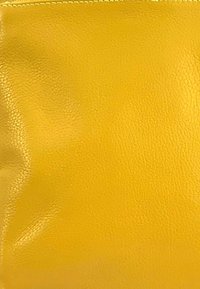 Pochette en cuir jaune avec une surface lisse et texturée, présentant de subtils plis et un bord cousu, conçue pour un rangement compact.
