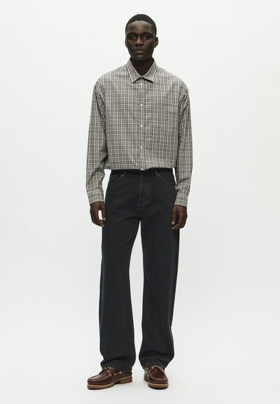 Nööbiga särk, millel on halli ja sinise ruudulise mustriga, koos tumedate teksade ja pruunide nööbilestega kingadega. Ühtlane taust.