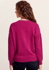Maglione fucsia a maniche lunghe, con polsini e orlo a coste. Tessuto morbido con una vestibilità rilassata e scollatura rotonda.