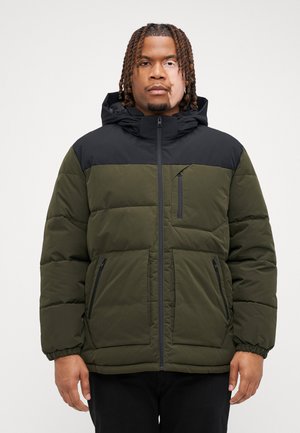 Chaqueta tipo puffer con un cuerpo verde y hombros negros, que cuenta con un bolsillo en el pecho con cremallera y dos bolsillos laterales, fabricada en tejido suave.