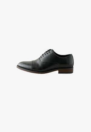 Czarny męski elegancki but ze skóry z sznurowadłami, z przyszwą typu cap toe i niskim brązowym piętkiem warstwowym, przedstawiony z boku na białym tle.