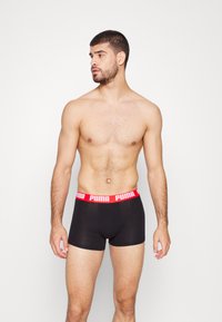 Schwarz Boxer-Shorts mit rohem elastischen Bund, der das Puma-Logo trägt; der Stoff scheint glatt und dehnbar zu sein, das enganliegende Design wird hervorgehoben.