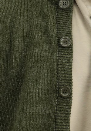 Olivgrüner Strickcardigan mit einem gerippten Kragen und fünf grauen Knöpfen auf der Vorderseite. Darunter ist ein hellbeiges Oberteil sichtbar.