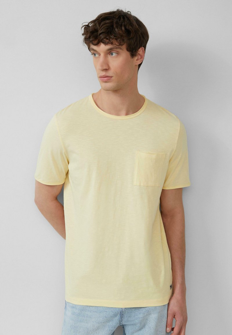 Lichtgele T-shirt met korte mouwen, ronde hals, heeft een linkerkant borstzak en een relaxte pasvorm met een zachte textuur.