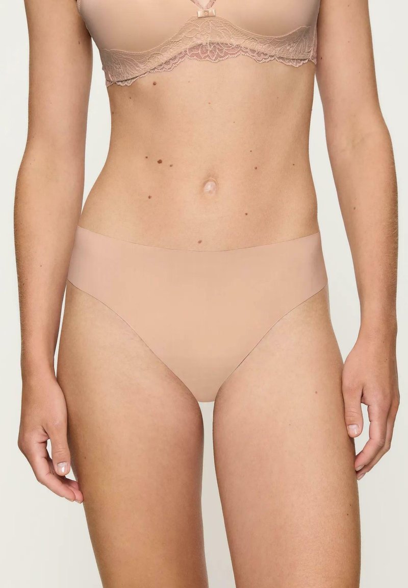 Beżowa, bezszwowa bielizna bikini o gładkiej fakturze i niższym kroju, charakteryzująca się minimalistycznym stylem i brakiem widocznych szwów.