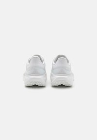 White athletic shoes with a mesh upper, rounded heel, and textured rubber sole, featuring minimal branding and a sleek design.