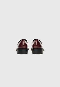 Burgundi patendi nahkkingad madala musta kontsaga ja sileda viimistlusega, ümarate varvastega ning minimalistliku disainiga, millel pole nähtavat riistvara.