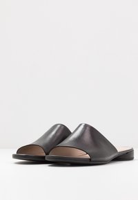 Černé kožené pantofle s otevřenou špičkou, hladkým povrchem, minimalistickým designem a plochou podrážkou. Doplněné jemným leskem pro moderní vzhled.