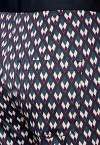 Marineblauwe shorts met een diamanten patroon in het wit en roze. Heeft een achterzak met een bijpassende stofstructuur en stikseldetails.