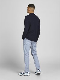 Marineblaues Langarm-Polo, leichte karierte Hose und sportliche Sneakers mit Marineblau- und Hellblau-Akzenten. Einfaches Design mit vollständiger Rückansicht.