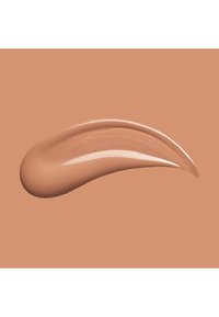 Vloeibare foundation swatch met een romige, gladde textuur; lichtbruine kleur met een satijnen finish, afgebeeld tegen een bijpassende beige achtergrond.