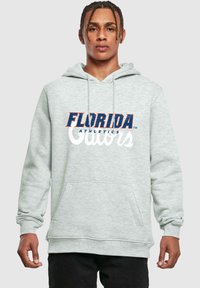 Sudadera gris con un bolsillo frontal y capucha con cordón. Logos de "Florida Athletics" y "Gators" en azul y naranja en el pecho.