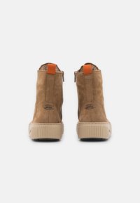 Brown suede ankle boots with orange loop pull, side zip, and textured beige rubber sole. Features logo detail and smooth finish.