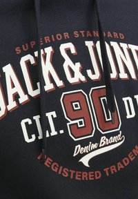 Felpa con cappuccio di colore blu navy con una grande stampa grafica. Presenta lettering audace in bianco e bordeaux e un accento di cordino testurizzato.