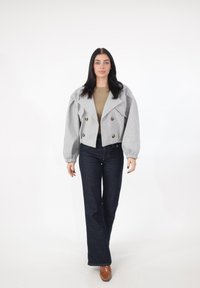 Grå kort dobbeltbrystet jakke med store knapper, opsmøgede ærmer og en struktureret finish, kombineret med mørke denim flared bukser.