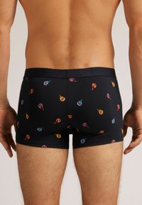 Bóxers negros hechos de una tela suave, con un patrón colorido de trompos giratorios. La cinturilla es de color negro sólido para un ajuste seguro.