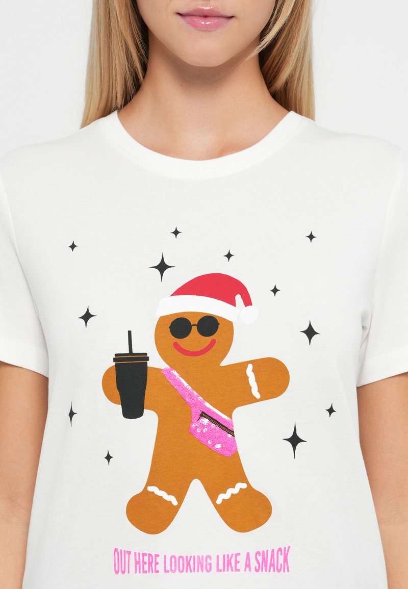 Weißes T-Shirt mit einem Lebkuchenmann, der einen Weihnachtsmannhut, Sonnenbrille, eine rosa Paillettenbauchtasche trägt, ein Getränk hält und von Sternen umgeben ist.