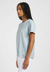 T-shirt azzurro chiaro a maniche corte realizzato in un tessuto morbido e leggero. Presenta un semplice collo a giro e un piccolo logo vicino all'orlo.
