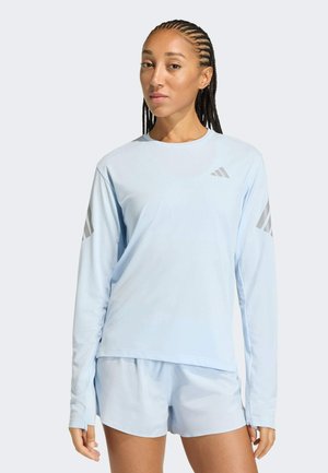 Lyseblå atletisk top med lange ærmer og rund hals, med sølvfarvede accentstriber på ærmerne, kombineret med matchende lyseblå shorts.