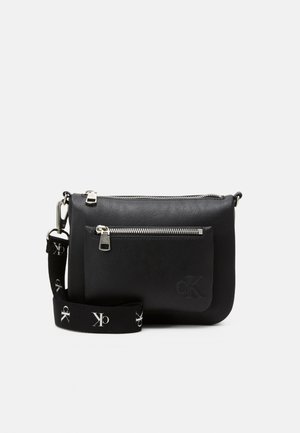 Czarna skórzana torba crossbody z przednią kieszenią na zamek i regulowanym paskiem z białymi logo CK.