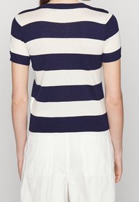Námořnický a krémový pruhovaný svetr s krátkým rukávem, s žebrovaným kulatým výstřihem a přiléhavým designem, se solidním námořnickým spodním lemem a hladkou текстurou.