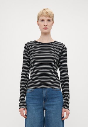 Black and white striped long-sleeve top with a round neckline. Soft fabric, fitted design, and contrasting horizontal stripes. Paired with blue jeans.