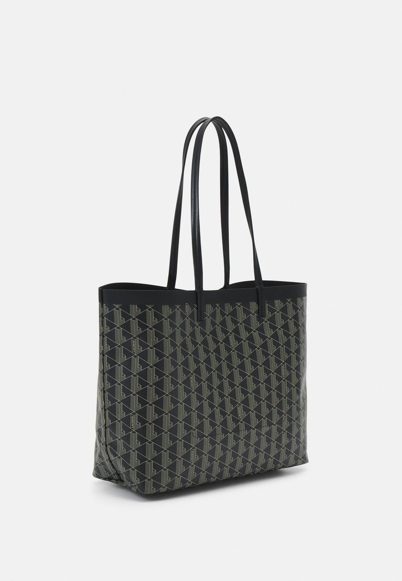 Czarna torba na ramię o geometrycznym wzorze, czarnych uchwytach, pojemnym designie i gładkiej fakturze. Idealna do codziennego użytku.