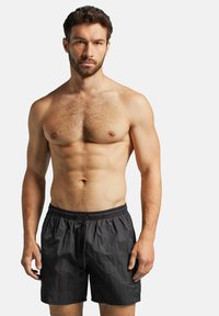 Černé plavky s elastickým pasem a stahovací šňůrkou, vyrobené z lehkého, mírně texturovaného materiálu. Žádné viditelné vzory ani akcenty.