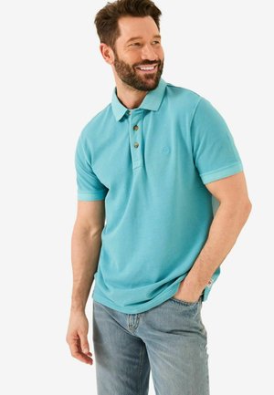 Light blue polo shirt with three-button placket, slim fit, cotton material, and short sleeves. Paired with blue jeans.