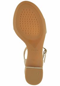 Sandal in pelle beige con cinturino alla caviglia, suola in gomma sagomata con piccole perforazioni circolari e etichetta in rilievo "GEOX ITALIAN PATENT."
