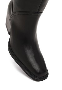 Stivale alla caviglia in pelle nera con finitura liscia, punta quadrata e tacco impilato. Presenta dettagli di cucitura discreti lungo i lati.